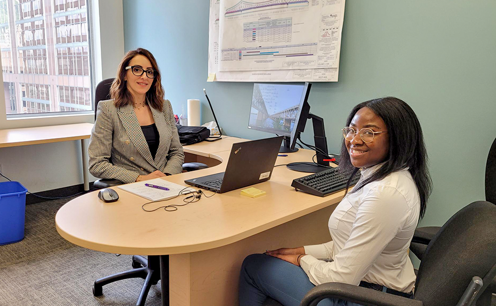 Two women sitting at a desk in an office.