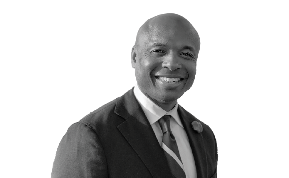 A black and white photo of a smiling man in a suit.