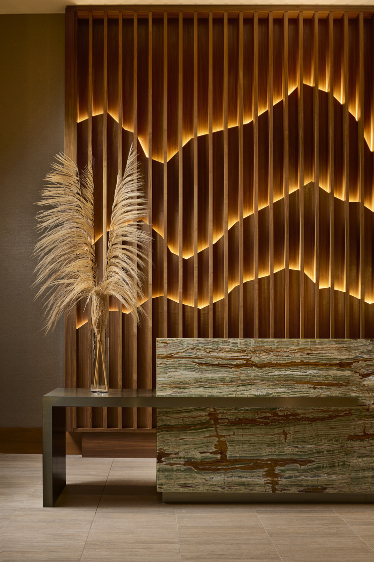 A table with a vase of dried grass in front of a wall.