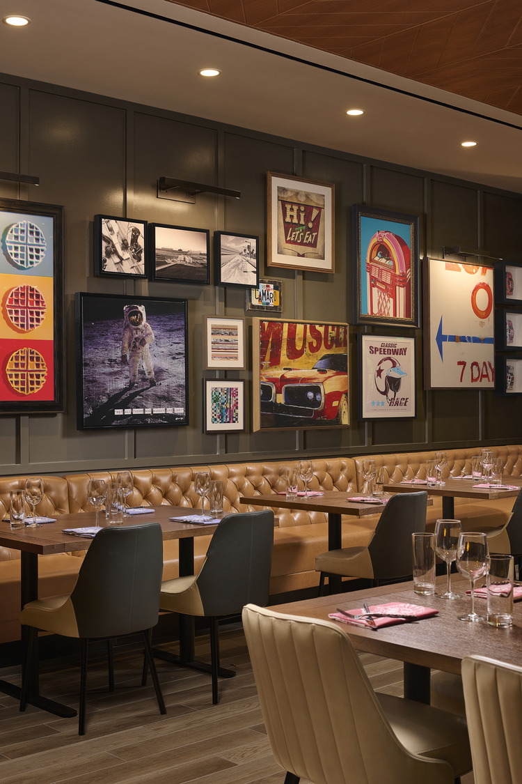 A restaurant with a booth seating and art on the wall.