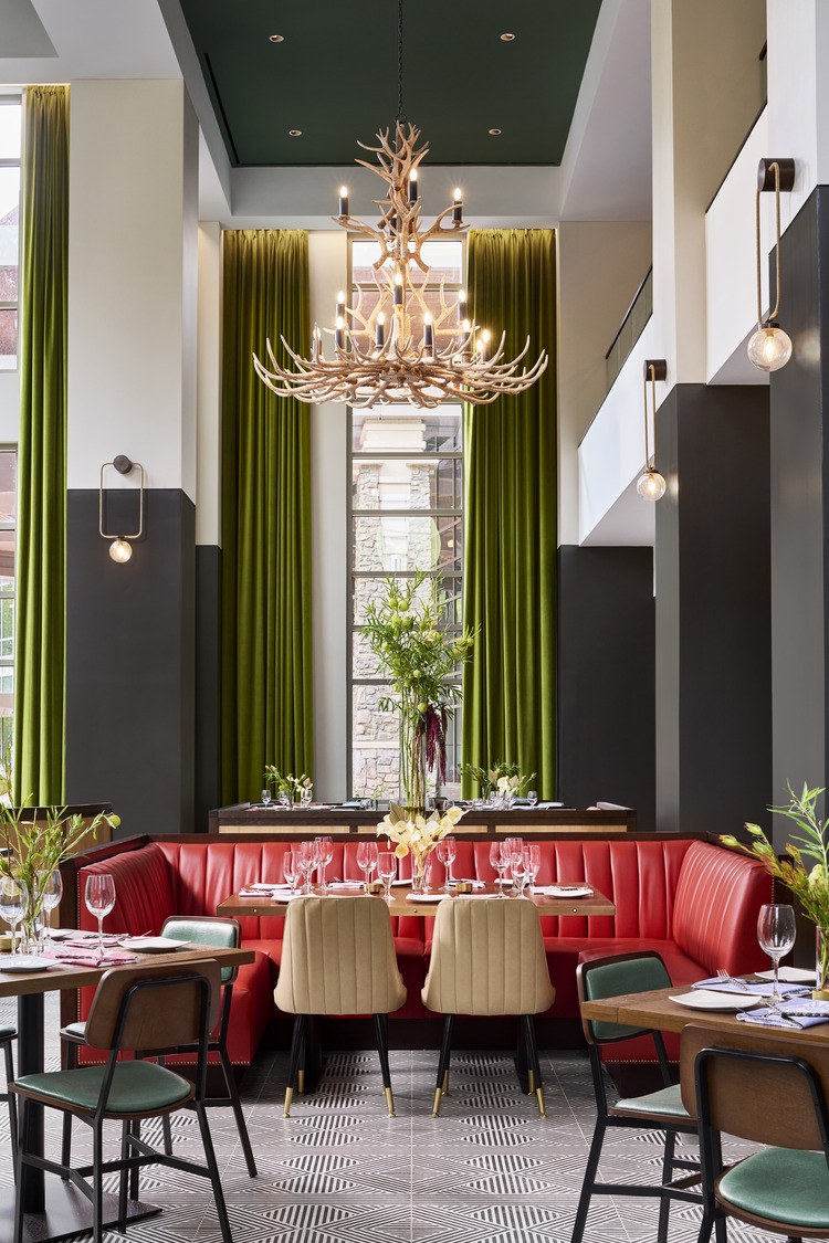 A restaurant with green curtains and chandelier.