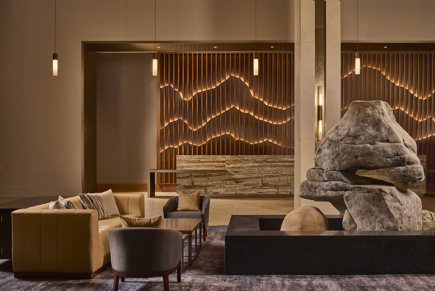 The lobby of a hotel with a stone wall.