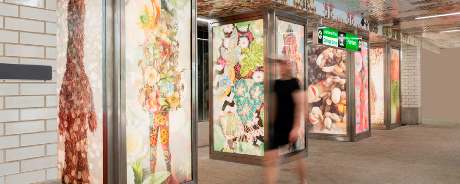 A woman is walking past a subway station with a lot of food on the walls.