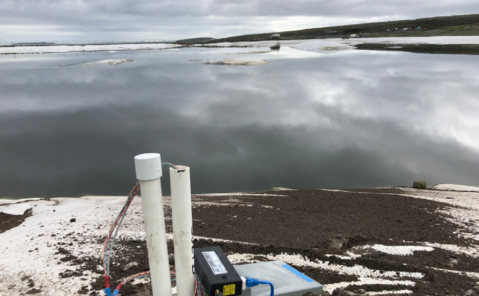 A device is sitting on the ground next to a body of water.