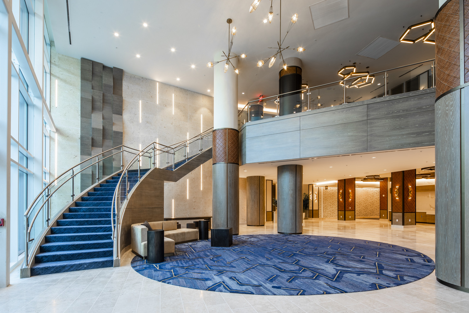 A lobby with a spiral staircase and blue carpet.