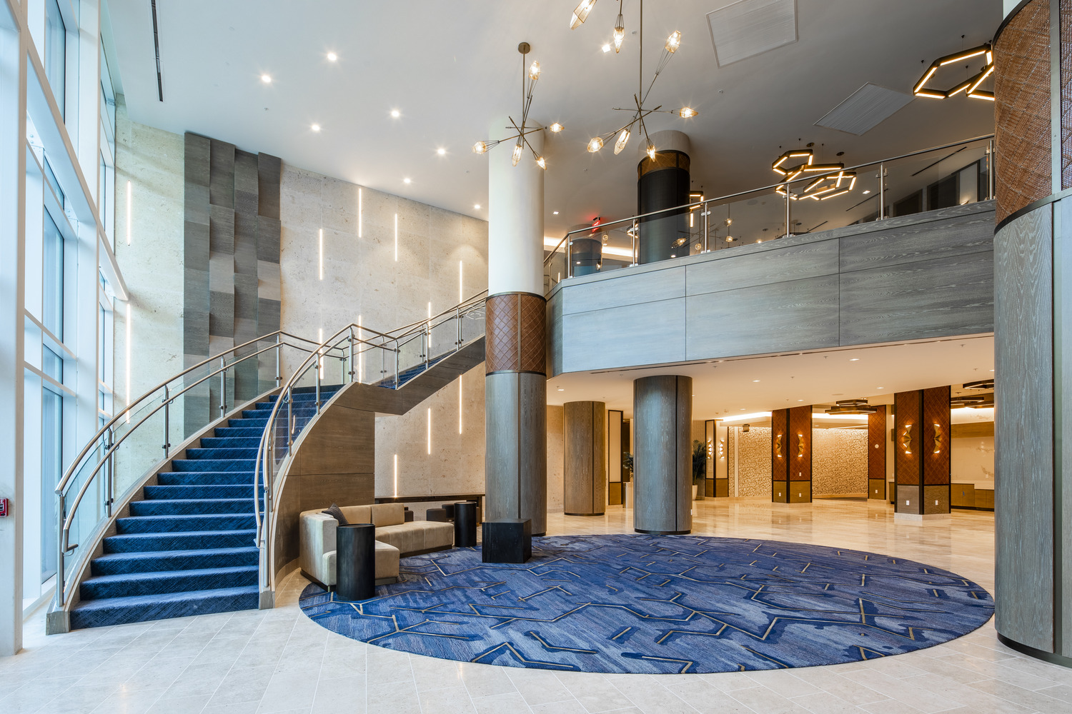 Un hall d'entrée avec un escalier en colimaçon et une moquette bleue.