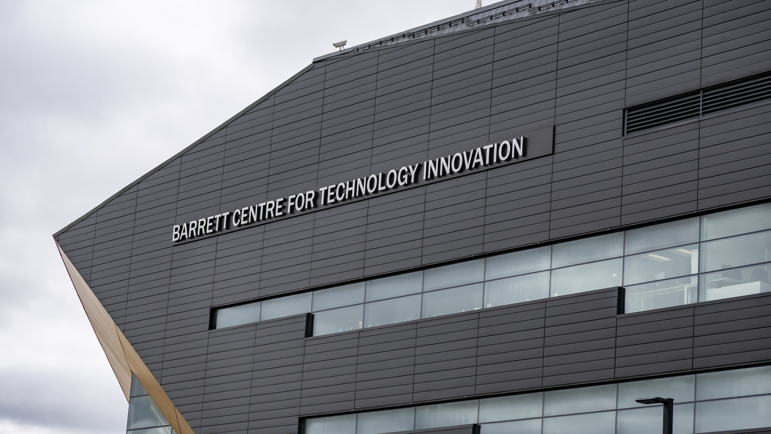 Modern architectural design of the barrett centre for technology innovation against a cloudy sky.