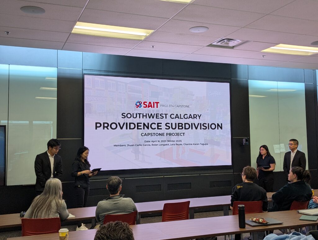 Five presenters stand in front of a screen displaying "Southwest Calgary Providence Subdivision Capstone Project" to an audience in the SAIT Connector Lab classroom setting.