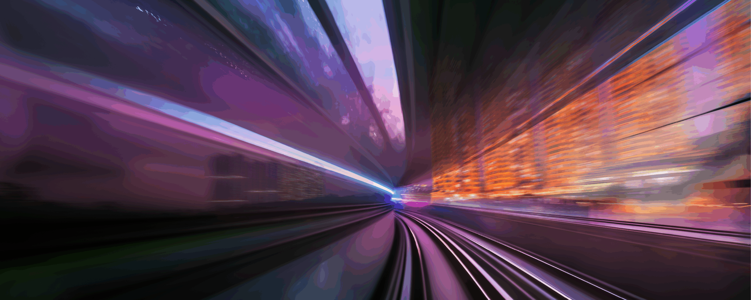 A blurred motion view from a train or transit system in a city at dusk, with purple and orange lights reflecting off buildings and tracks, captures the dynamic energy of modern intermodal infrastructure.