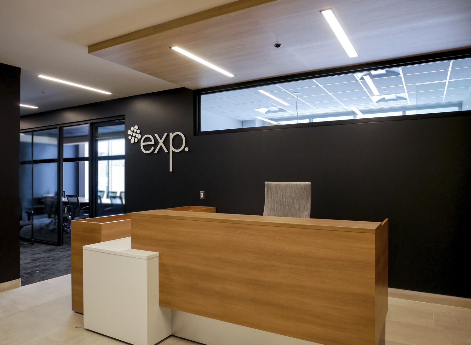 Modern office reception area with a wooden desk, a gray chair, and the 