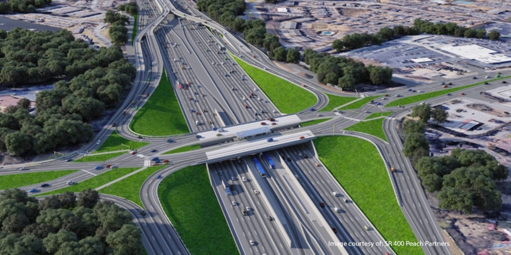 Aerial view of a large highway interchange with multiple lanes, overpasses, vehicles, and green areas in an urban setting.