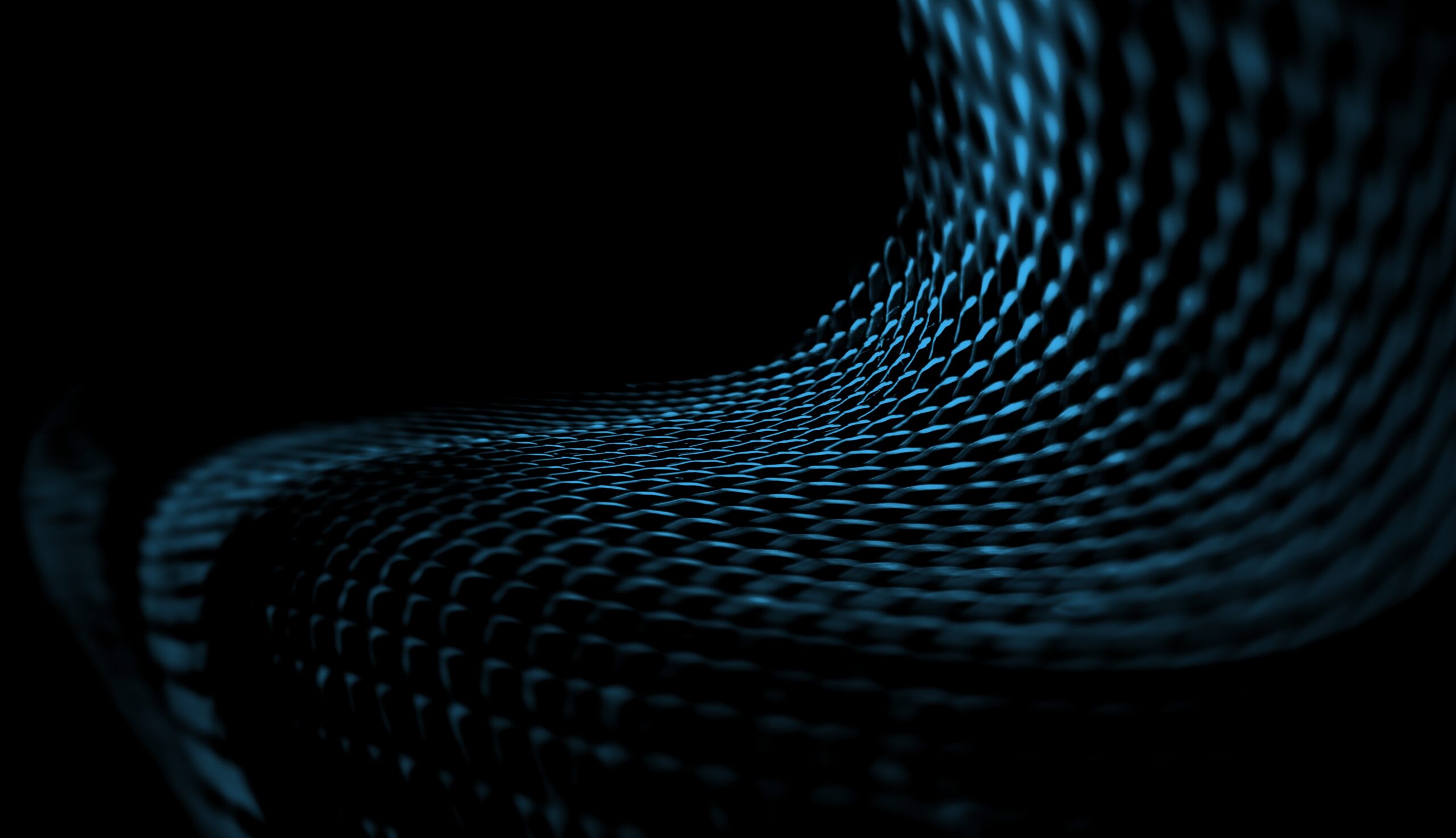 A close-up of a dark, textured surface with a wavy, grid-like pattern illuminated by blue light against a black background.