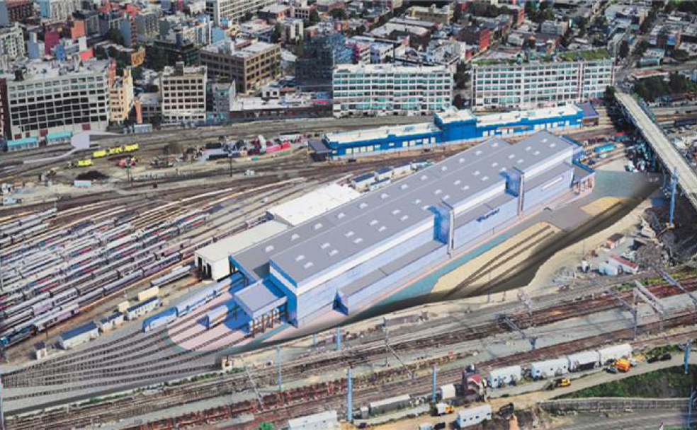 Aerial view of Sunnyside Yard, a large train station served by Amtrak, featuring multiple railway tracks and a modern building surrounded by urban infrastructure and high-rise buildings.
