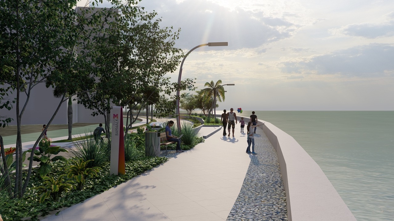 A paved waterfront promenade along Brickell Bay with people walking, trees, benches, modern streetlights, and the ocean on the right under a cloudy sky.