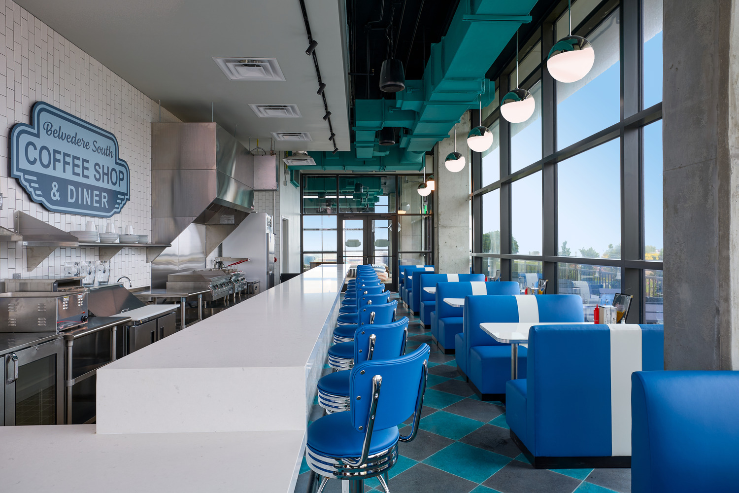 A retro-style diner with blue booths and chairs, white countertops, and a sign reading 