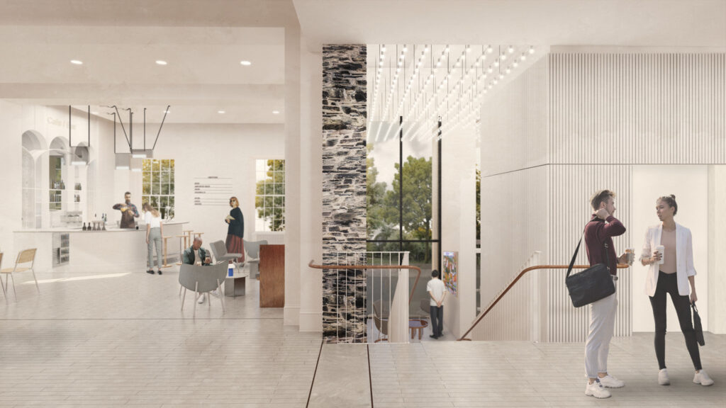 Two people talk by a staircase in a modern, bright building featuring sleek interior design; others interact in a nearby café area with large windows and minimalist decor.