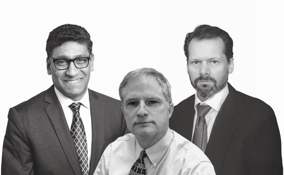 Three men in business attire pose against a plain, light background. Two wear suits and ties, while the man in the center wears a shirt and patterned tie. All face the camera.
