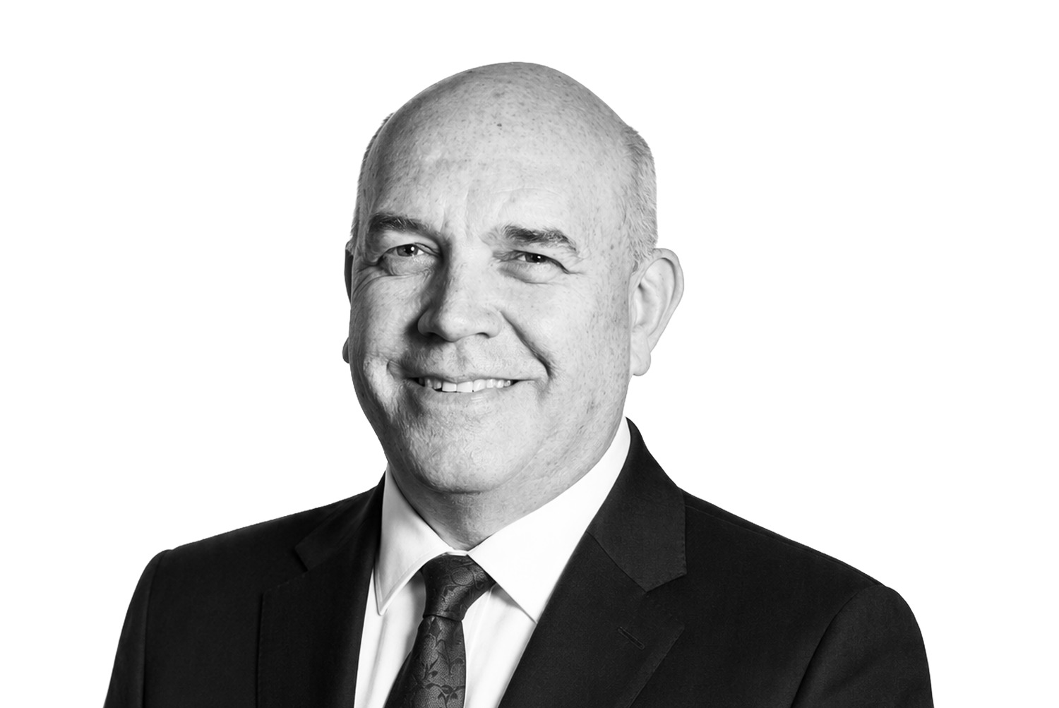 Bald man in a suit and tie smiling at the camera against a plain white background.