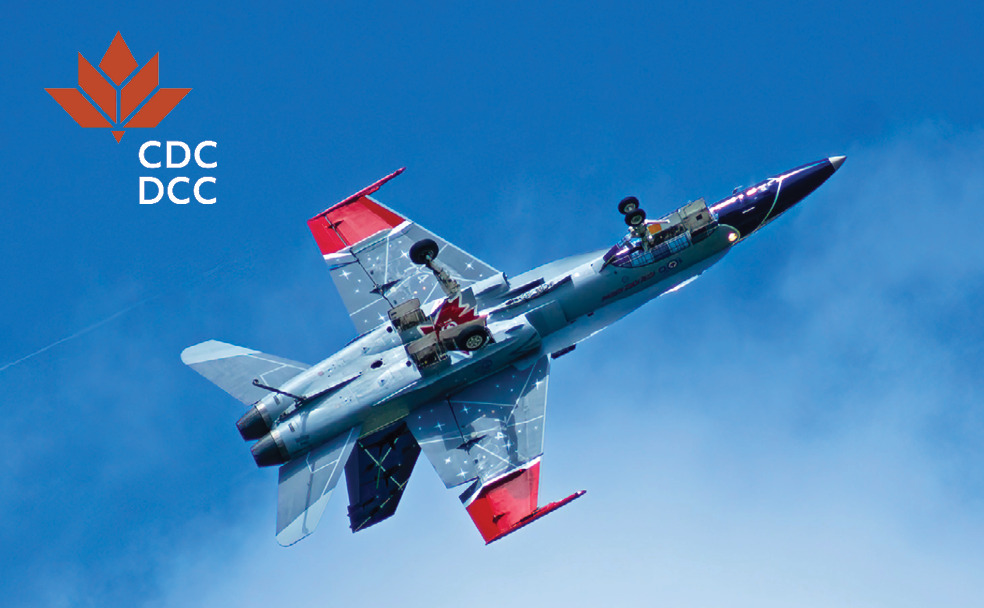 Un avion de chasse canadien CF-18 Hornet en vol sur fond de ciel bleu, avec le logo de la Société immobilière du Canada dans le coin supérieur gauche.