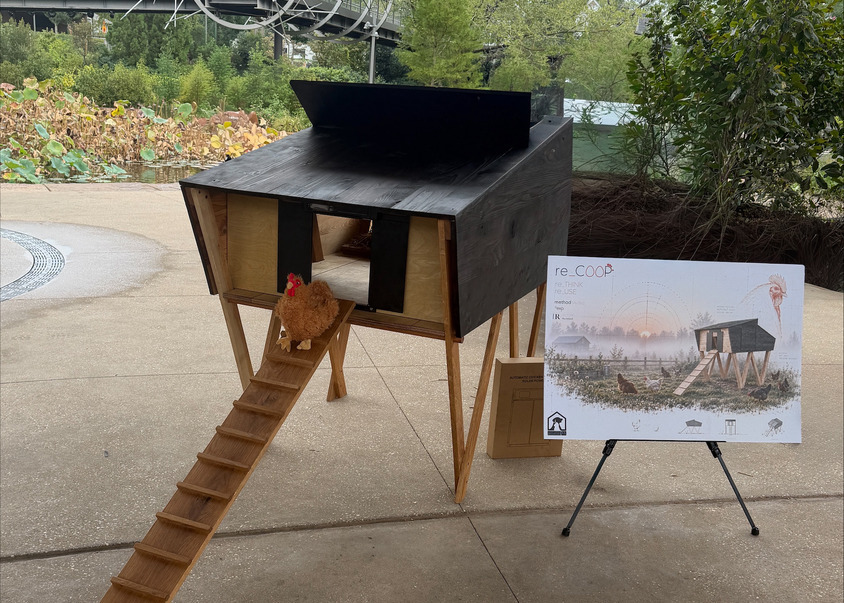 A barkitecture-inspired wooden chicken coop on stilts with a ramp and a stuffed chicken, beside an easel displaying a design illustration labeled “re_COOP.”